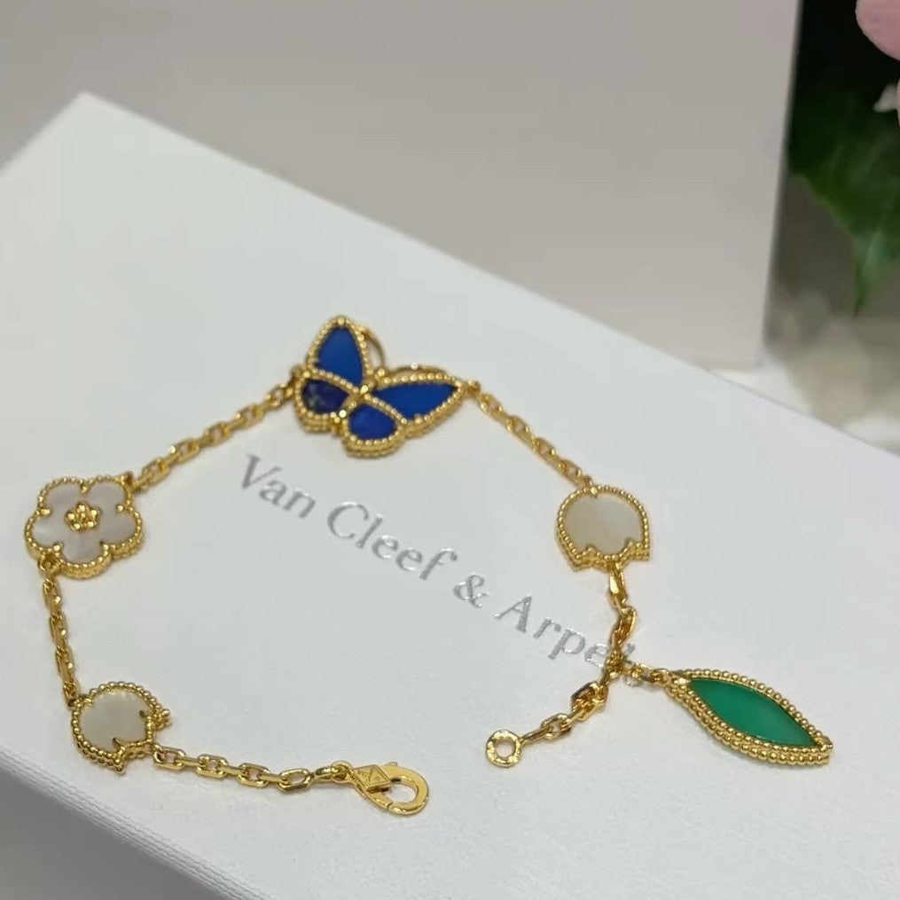 Vancleef LuckySpring gold-plated bracelet with blue butterfly, white flower charms, and green stone pendant on Van Cleef & Arpels card
