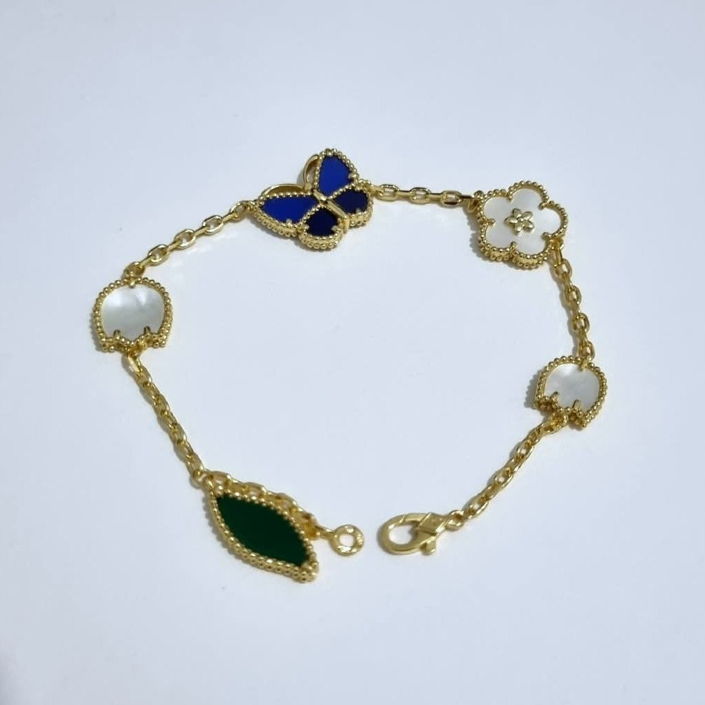 Vancleef LuckySpring gold-plated bracelet with blue butterfly, white flower charms, and green stone pendant on Van Cleef & Arpels card